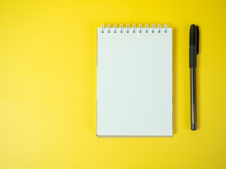 Notebook and pen, on a yellow background. Top view copy space