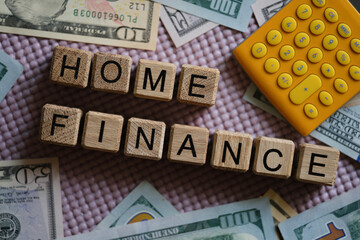 Dollar bills and calculator lying near wooden cubes with words home finance closeup