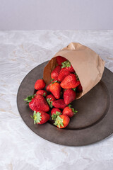 Reife Erdbeeren in Papietüte auf einem Teller
