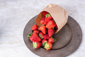 Reife Erdbeeren in Papietüte auf einem Teller
