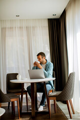 Young man using laptop and drink tea in the living room