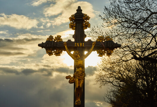 Jesus cross photographed in nature. The sun in the background. A tree can also be seen in the backlight. INRI.