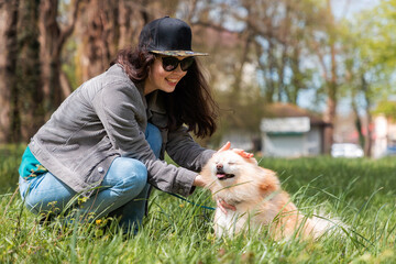 A happy woman strokes her Pomeranian in the spring park. Training of pedigreed dogs