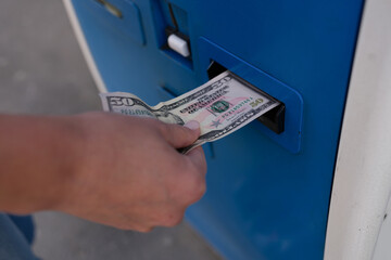 Woman inserting dollar bills into ATM on street closeup