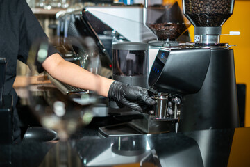 Close-up image of the coffee grinder machines in a coffee shop. Barista grinding freshly roasted coffee beans from a professional modern electric grinder into a powder. Cafe brewing Service Concept