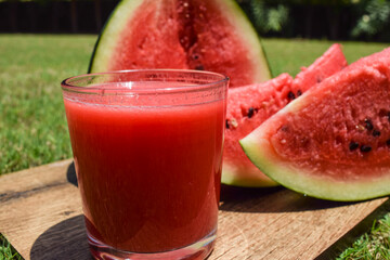 Watermelon juice drink with freshly cut water melon fruit served in outdoor environment background. Fresh and delicious red colour Tarbooz ka Sharbat from India or PakistanPopular famous summer drinks