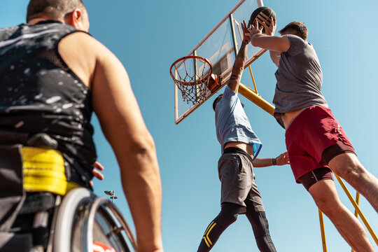  A physically challenged person play street basketball with his friends.			
