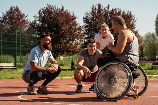 A physically challenged person, basketball coach plays streetball with his students.They are talking about tactics.	