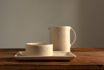 Artisan style cups and plates on wooden table and window light still life with homemade bread on the plates.