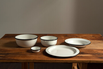 Artisan style cups and plates on wooden table and window light still life with homemade bread on the plates.