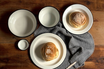 Artisan style cups and plates on wooden table and window light still life with homemade bread on the plates.
