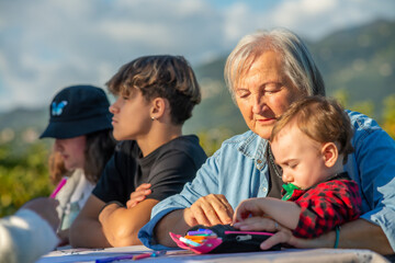 Grandparents and grandchildren playing together outdoor on a sunny afternoon at table games.