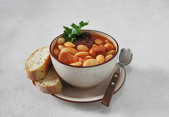 Traditional recipe of beans with chorizo and blood sausage of Fabada Asturiana on a white table....