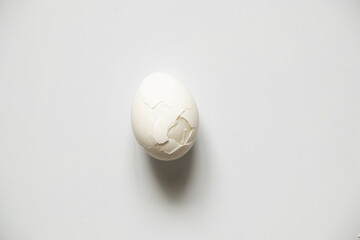 One broken white chicken egg on a white background