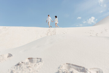  Young couple walks in the summer on the sandy beach