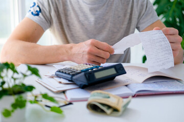 A man counts a bill on a calculator on the table. Payment of utility services. Saving energy and...