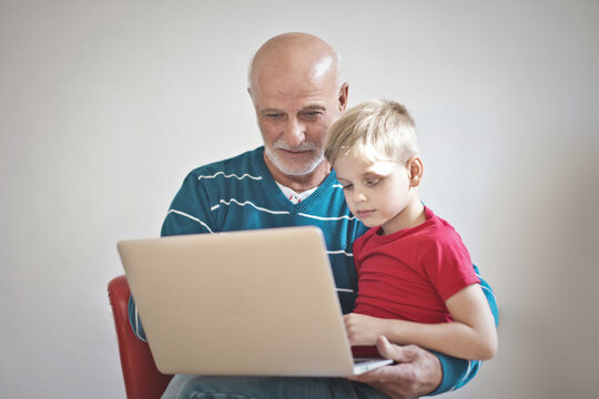 portrait of grandfather and grandson with a computer in hand,