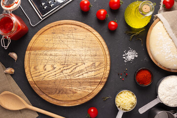 Pizza cutting board with ingredients on table. Dough for pizza at table top - 501207204