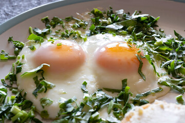 Fried eggs with greens close-up, healthy breakfast