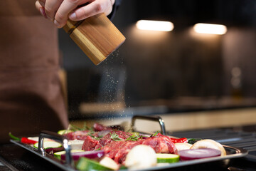 Close-up Man preparing Raw Steak Meat before Cooking seasoning with Sea Salt, Cooking Steak at Home in Modern Kitchen.