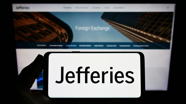 Stuttgart, Germany - 03-30-2022: Person holding smartphone with logo of US company Jefferies Financial Group Inc on screen in front of website. Focus on phone display.