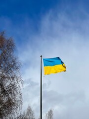 Ukraine flag large national symbol fluttering in blue sky.