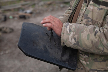 A soldier holds a Kevlar plate from body armor