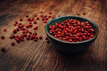 Pink peppercorns in a ceramic bowl on a wooden table