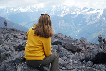 Naklejka premium Young tourist woman is hiking on the top of the mounting and looking at a beautiful landscape