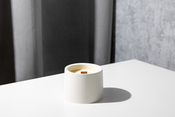 Candle soy homemade in ceramic burning in grey modern interior room, atmosphere and minimalistic composition 