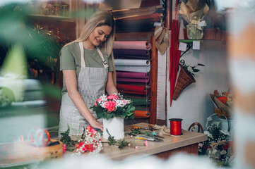 Florist woman creating flower arrangement in a round box