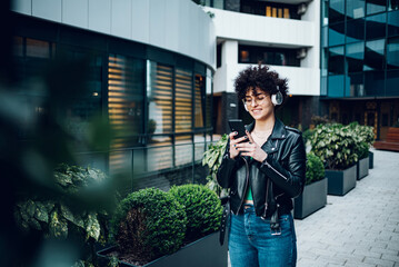 Woman walking in the city streets and using smartphone and headphones