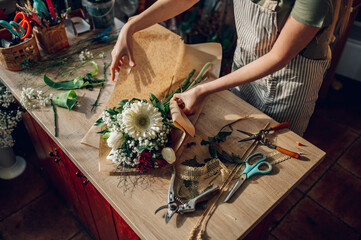 Woman florist hands making a bouquet while working in a flower shop