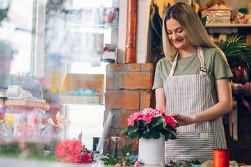 Florist woman creating flower arrangement in a round box