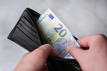 Takes out a 20 euro banknote from a leather wallet on a light background