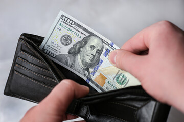 Puts in wallet or pulls out 100 dollar bill