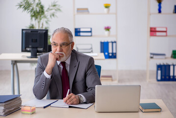 Old male employee sitting in the office