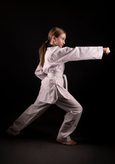 girl in kimono practicing taekwondo on black background. Sports banner. 