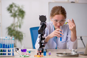 Young female chemist in drugs synthesis concept