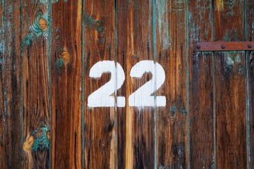 White colour number twenty two on an old abandoned weathered painted natural rusty brown wooden...