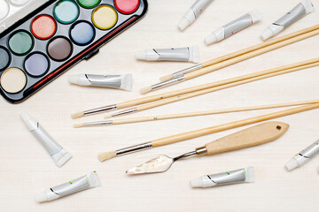 Watercolor oil tubes paints, paintbrushes, palette knife, colorful. Creativity creation process. Artist's stuff on white table.Top view Flatlay of drawing supplies