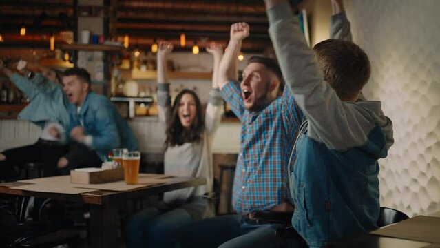 Friends are watching together emotionally watching football on TV in a bar and celebrating the victory of their team after scoring a goal. Watch hockey. The scored puck. Fans in the pub