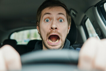 Close up portrait of shocked male driver with surprised face and open mouth.