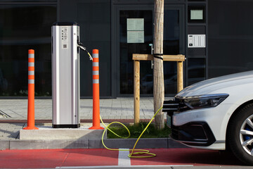 Modern car cable charging on plug in hybrid technology in front of a modern apartment building in a...