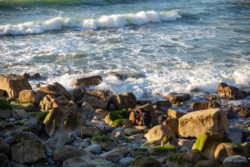 Photographer between the rocks of the beach photographing the waves of the sea