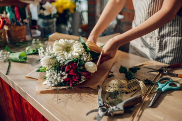 Woman florist hands making a bouquet while working in a flower shop