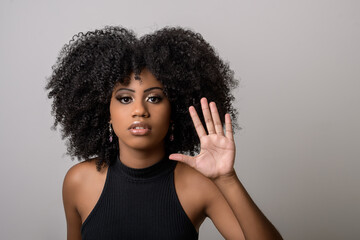 black woman makes gesture with open hand, denounces assault, moral harassment, cowardice, violence...