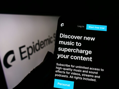 Stuttgart, Germany - 03-30-2022: Person holding cellphone with webpage of Swedish music company Epidemic Sound AB on screen in front of logo. Focus on center of phone display.