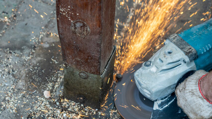 Close-up view of a worker working with angle grinder. Electric wheel grinding on steel structure. Sparks.