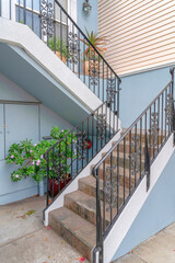 Stairs outside the house with potted plants, wrought iron railing, and stone tiles steps